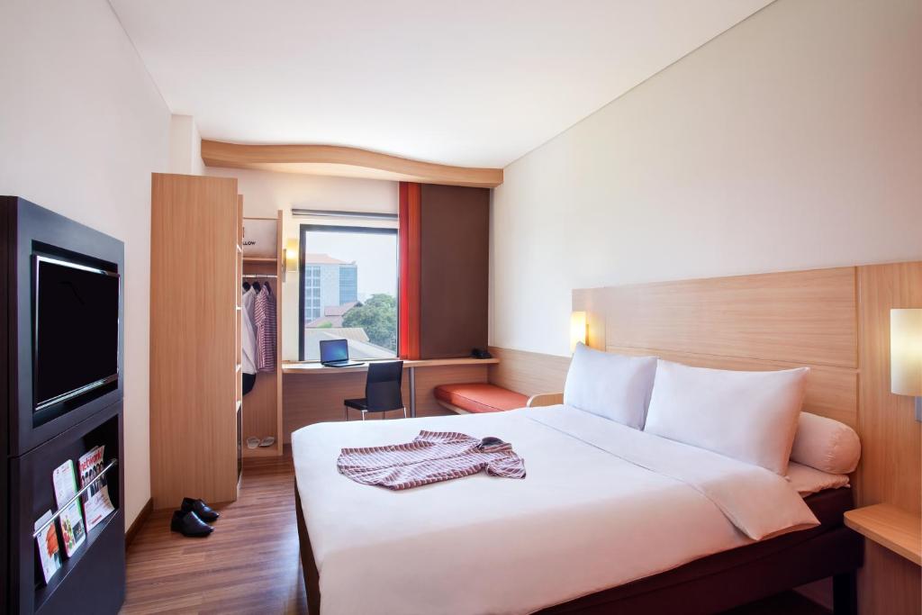 ジャカルタにあるSentral Cawang Hotelのベッドとテレビが備わるホテルルームです。