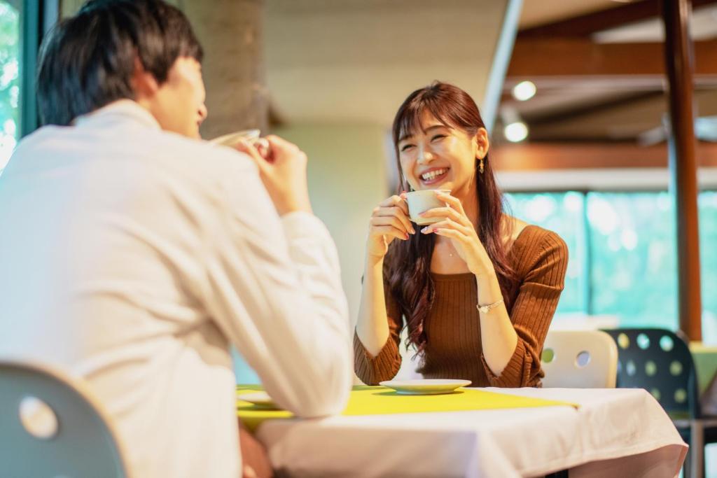 een man en een vrouw die aan een tafel koffie drinken bij Hotel Io Alpheratz in Kasama