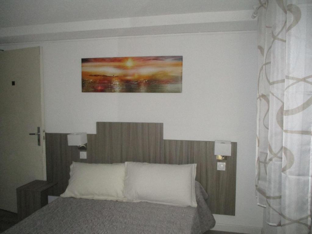 a bedroom with a bed and a painting on the wall at Hotel Du Commerce in Pont-Saint-Esprit