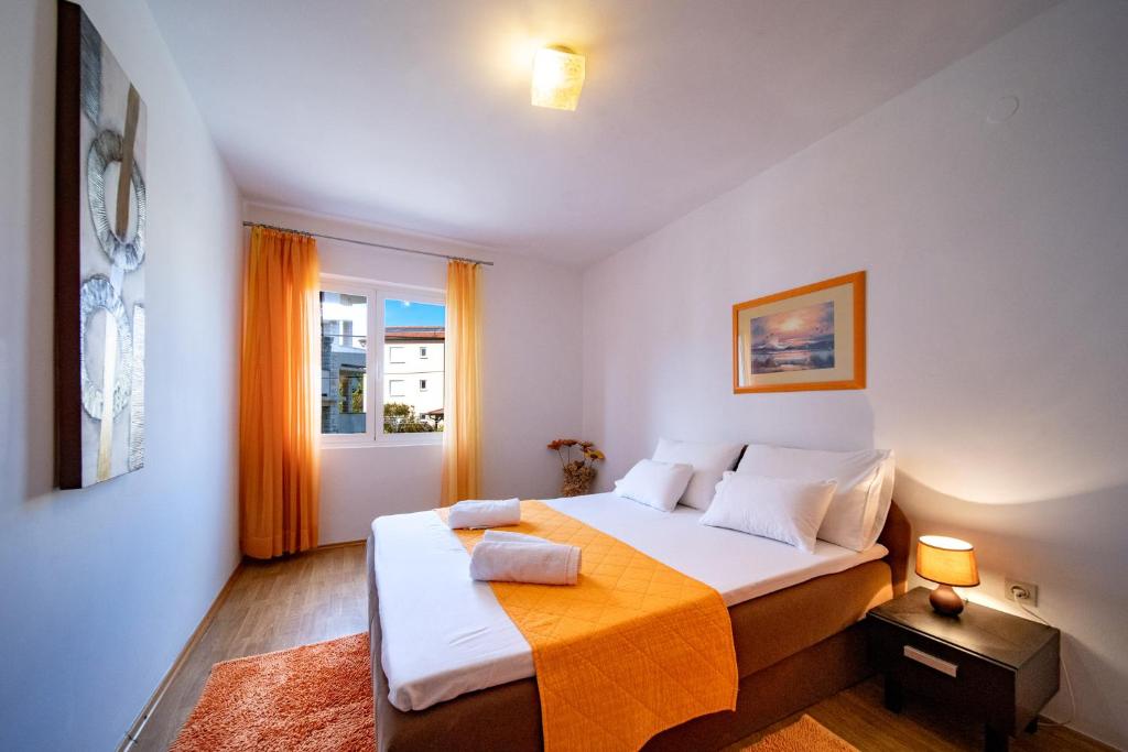 - une chambre avec un lit et une couverture orange dans l'établissement Apartments Lazarić, à Lopar