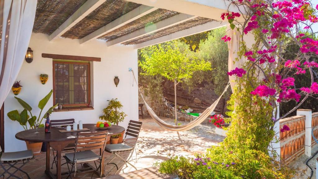 a patio with a table and chairs and flowers at Casa El Torin Frigiliana by Ruralidays in Frigiliana
