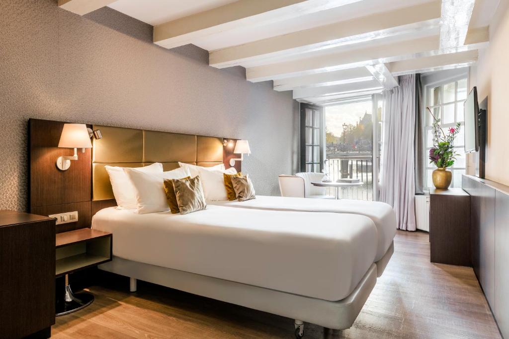 a hotel room with a large bed and a balcony at NH Collection Barbizon Palace Apartments in Amsterdam