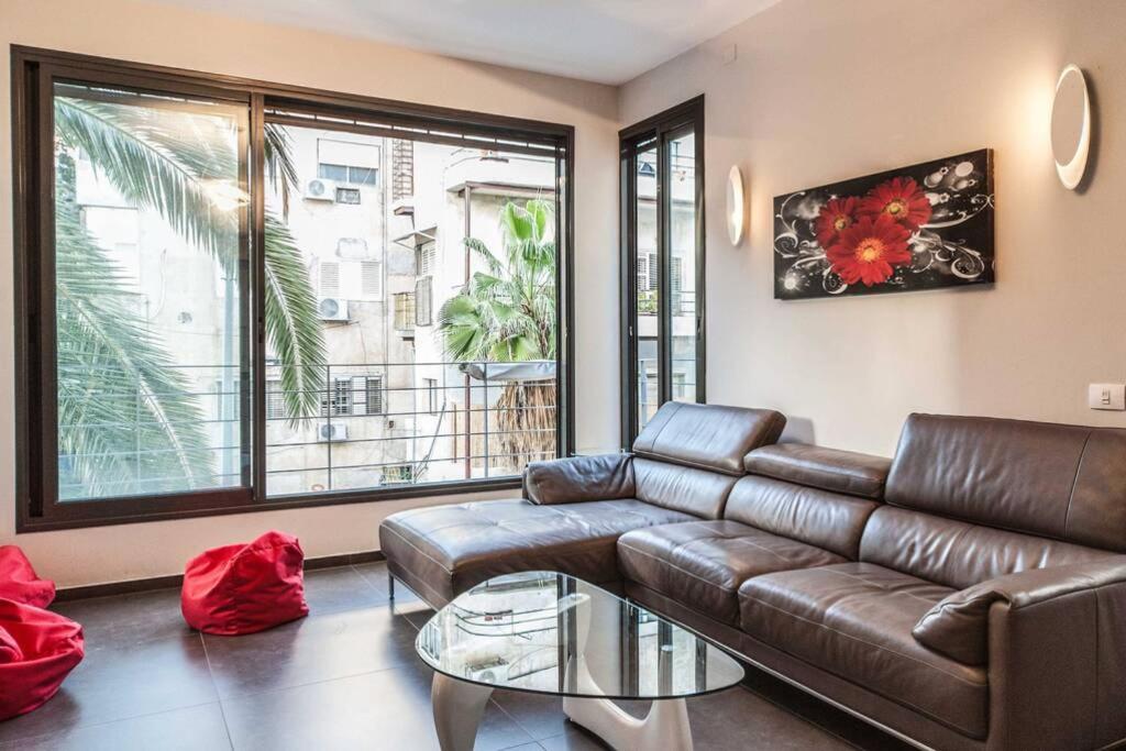 ein Wohnzimmer mit einem Ledersofa und einem Glastisch in der Unterkunft Luxury 3BR Apt Centrally Located & 5-min to Beach by Sea N' Rent in Tel Aviv