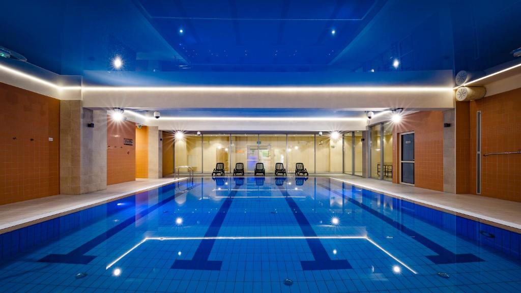 a swimming pool with chairs in a building at Interferie Aquapark Sport Hotel Malachit in Świeradów-Zdrój