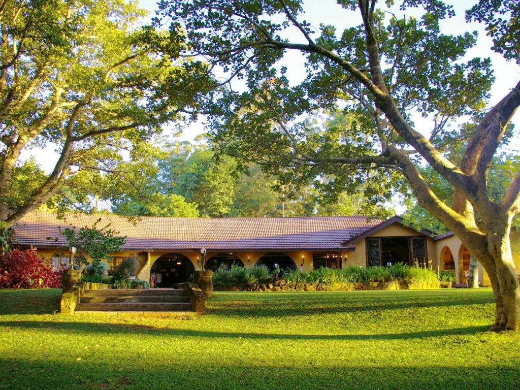 een huis met een groene tuin met een boom bij Bohm's Zeederberg Country House in Hazyview