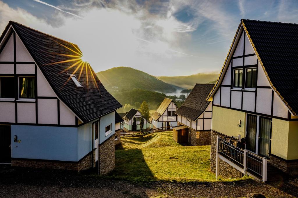 eine Reihe von Häusern mit Bergen im Hintergrund in der Unterkunft Dormio Resort Eifeler Tor in Heimbach