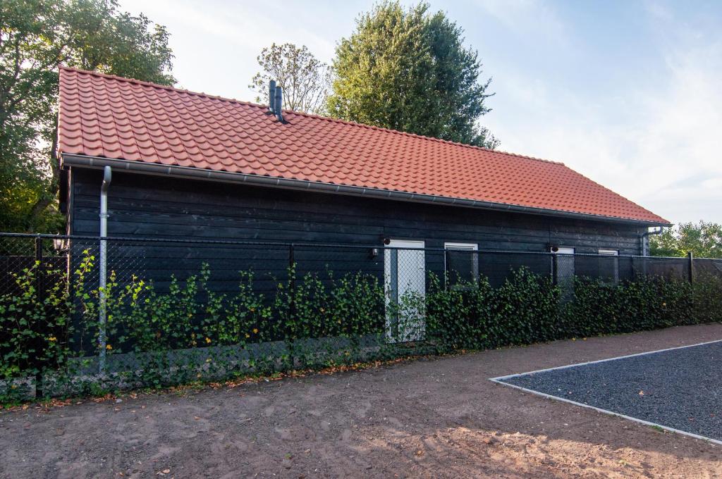 ein Gebäude mit rotem Dach und einem Zaun in der Unterkunft Vakantiehuis De Bergplaats in Hapert