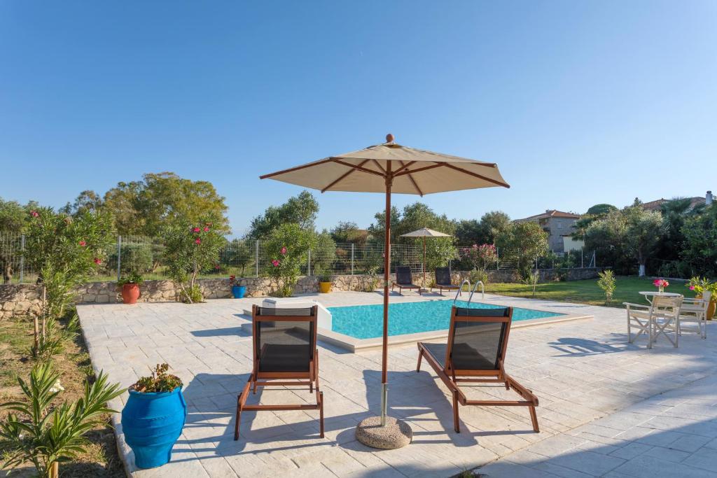 ein Paar Stühle und ein Regenschirm neben einem Pool in der Unterkunft Liuba Houses in Vasilikos