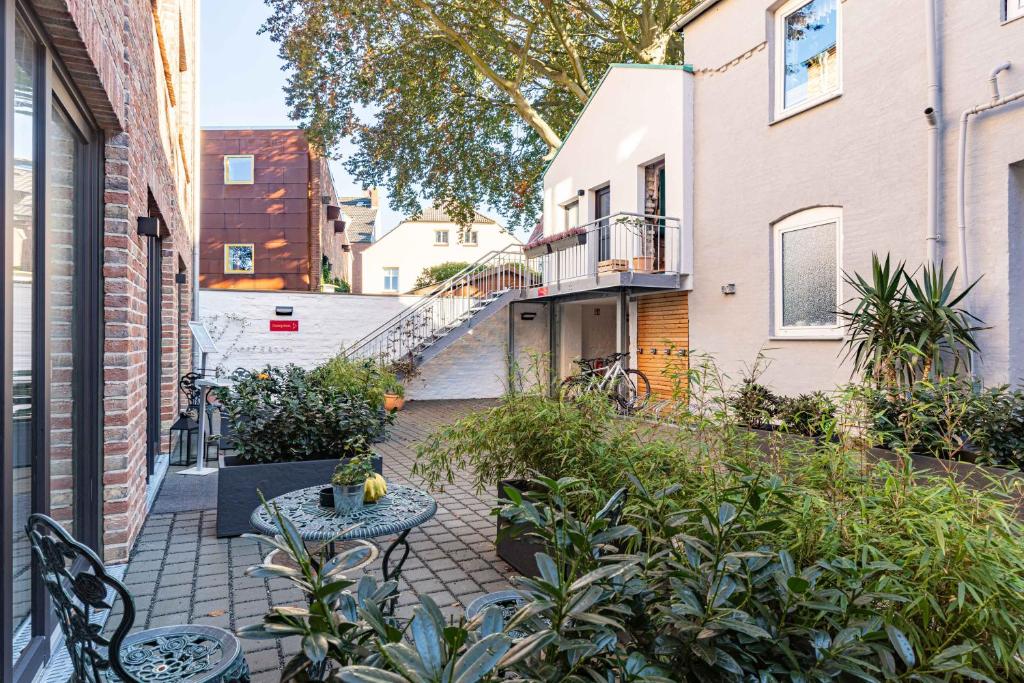 a patio with benches and plants in front of a building at LÜTTES LOFT Boutique Hotel in Eckernförde