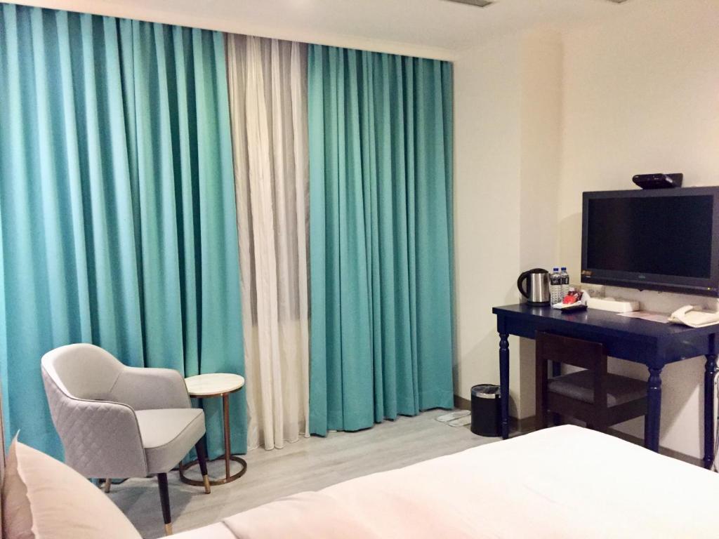 a hotel room with a desk and a computer and green curtains at Garden Hotel in Taichung