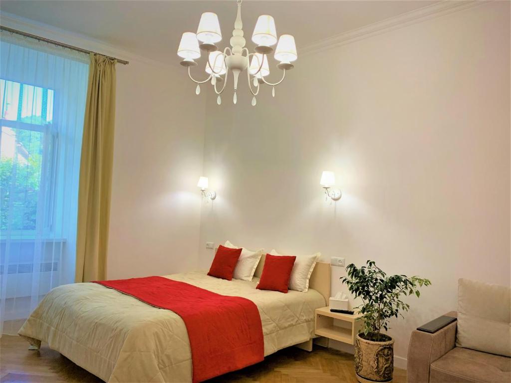 Schlafzimmer mit einem Bett mit roten Kissen und einem Kronleuchter in der Unterkunft Siesta apartment on Stefanyka in Lwiw