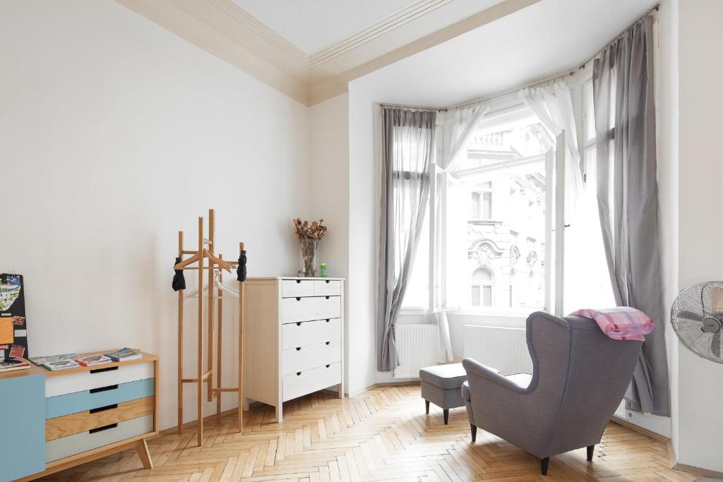 a white room with a chair and a dresser and a window at The BEST place in Prague - Old Town in Prague