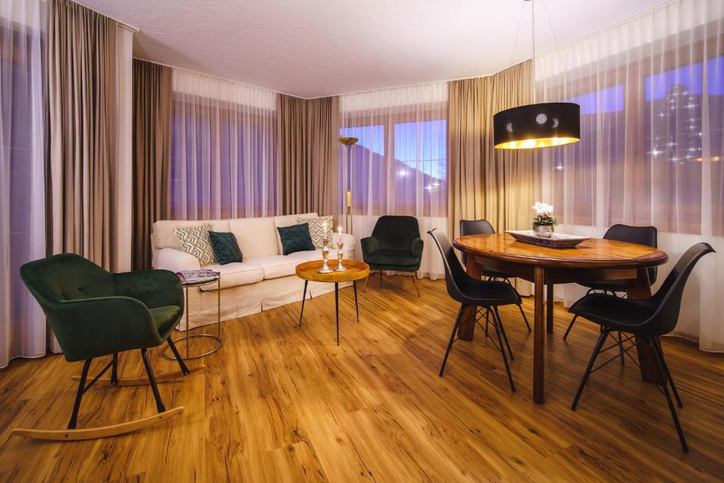 un soggiorno con tavolo, sedie e divano di Das Landhaus Apartments Prägant a Bad Kleinkirchheim