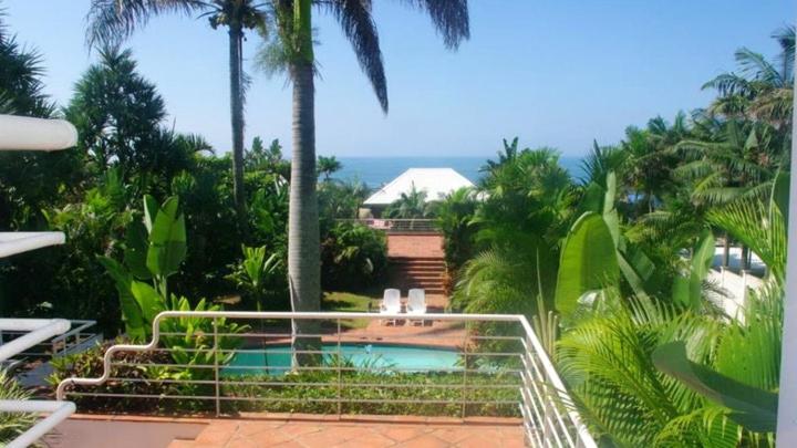 a swimming pool in a resort with palm trees at Thoko-Zani Beach House in KwaDukuza