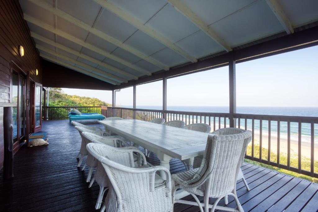 a long table and chairs on a deck with the ocean at Mar Azul 6, Ponta do Ouro road, Ponta Malongane in Ponta Malongane