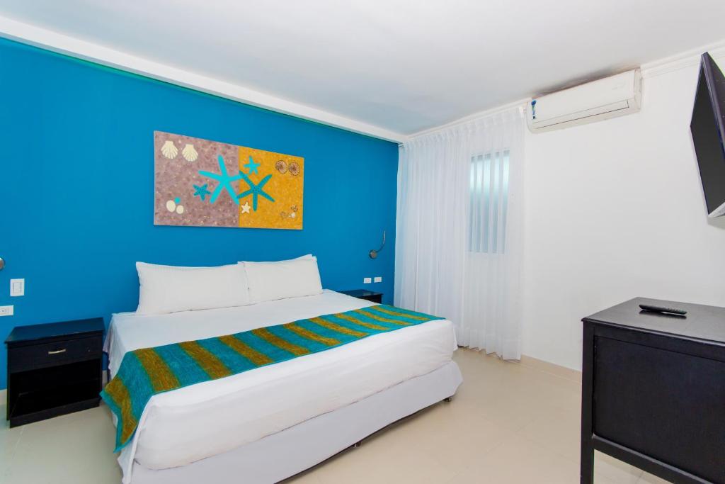 a bedroom with a bed and a blue wall at Hotel Bocagrande By GEH Suites in Cartagena de Indias