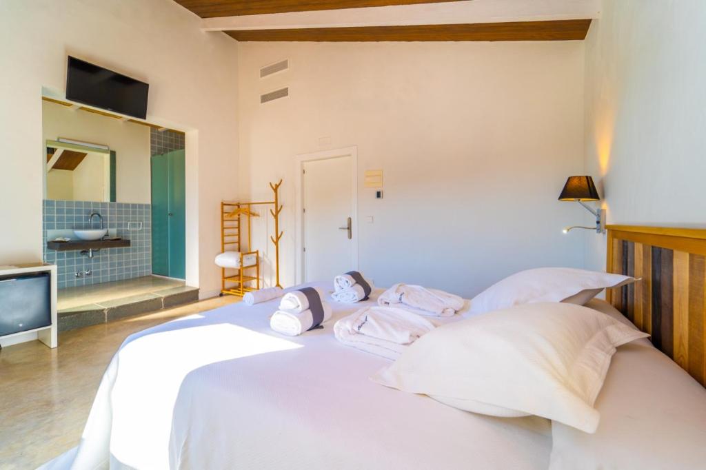 a white bed with white pillows and a television at Hostal Foies de Baix in Relleu