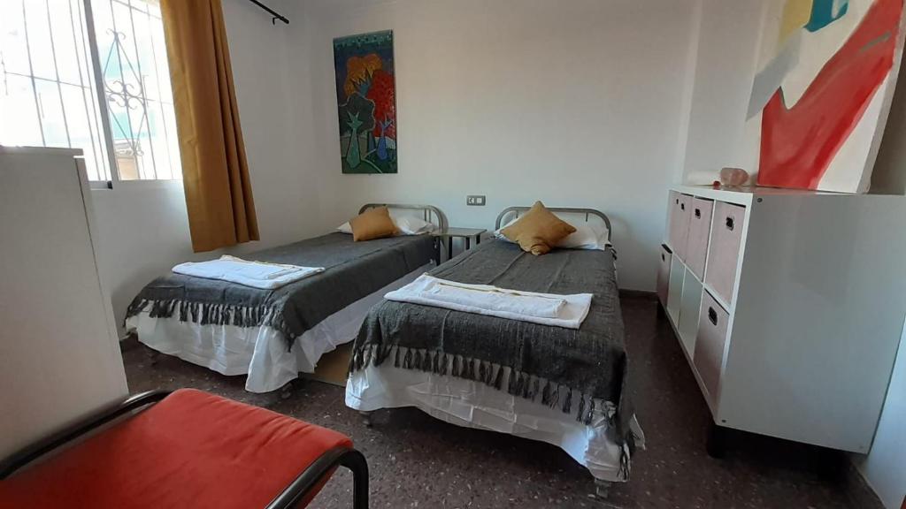pokój z 2 łóżkami i krzesłem w obiekcie el molino de viento flat w mieście San Pedro del Pinatar