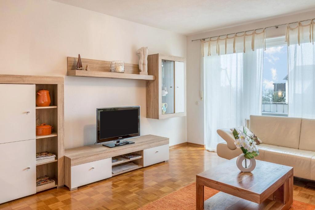 a living room with a television and a couch at Haus Unterseeblick - Fewo Seeblick in Gundholzen