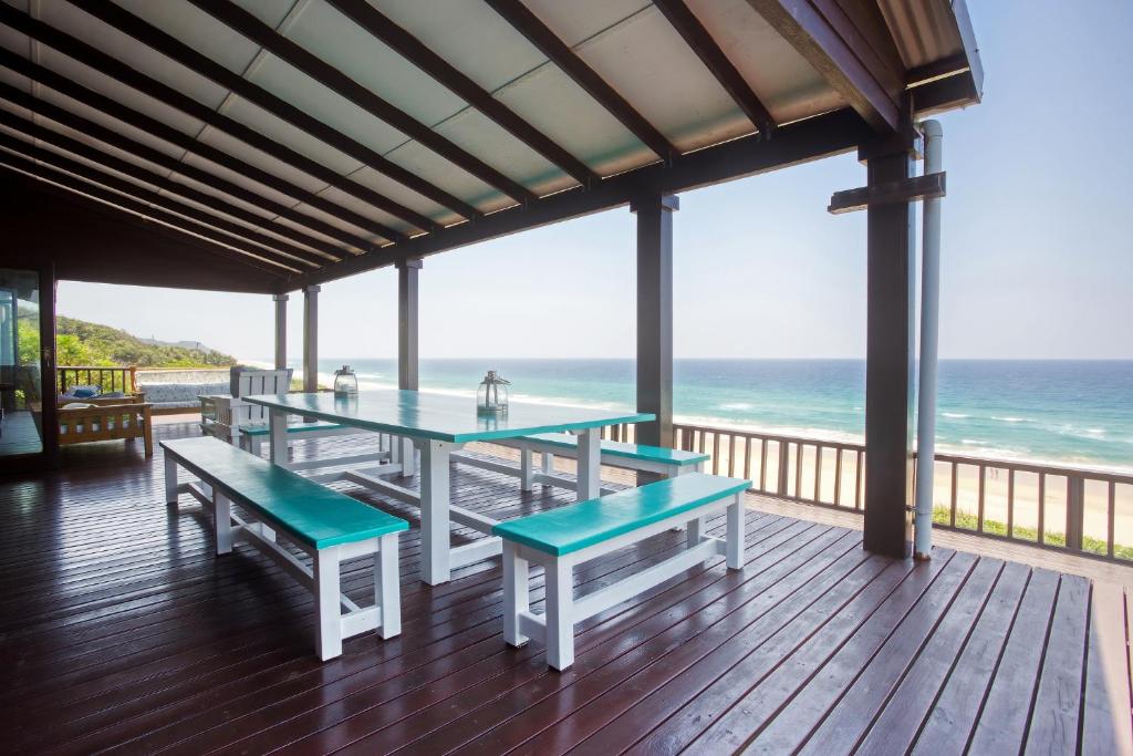 a porch with tables and benches on the beach at Mar Azul 5 in Ponta Malongane