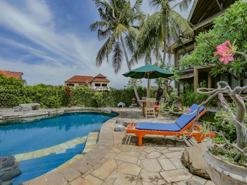 a resort pool with a chair and an umbrella at Vedanta Villa in Lovina