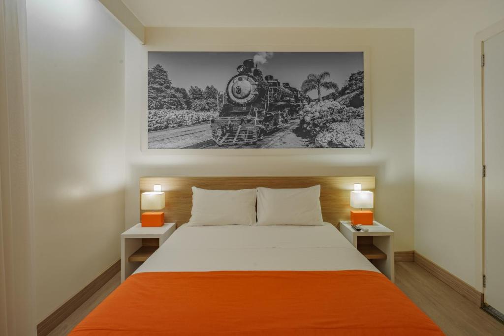 um quarto com uma cama grande e um cobertor laranja em Slim Bento Gonçalves em Bento Gonçalves