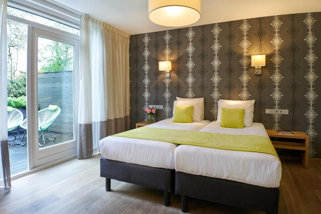 a bedroom with a large bed and a balcony at Alp de Veenen Hotel in Amstelveen
