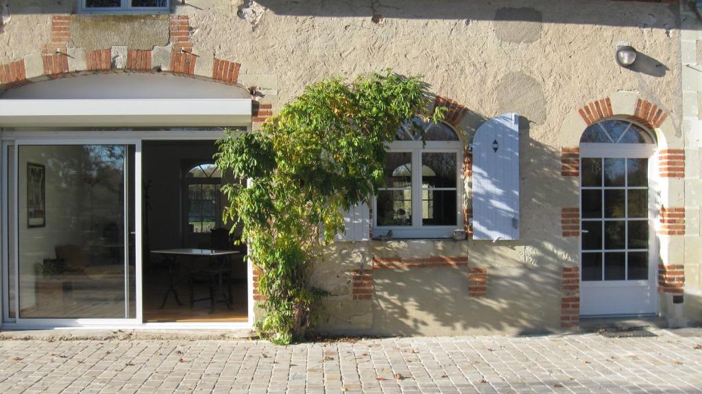 un edificio con una puerta y un arbusto delante de él en Le Petit Bois en Château-la-Vallière