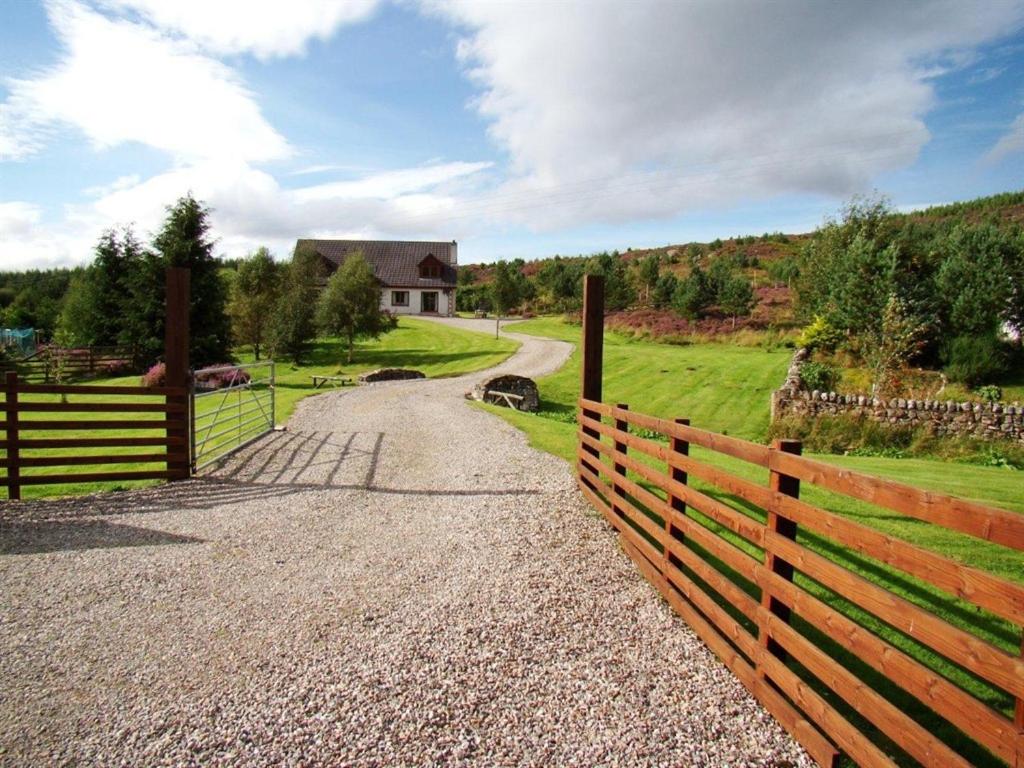 a wooden fence next to a road with a house at Binnilidh Mhor B&B in Glenmoriston