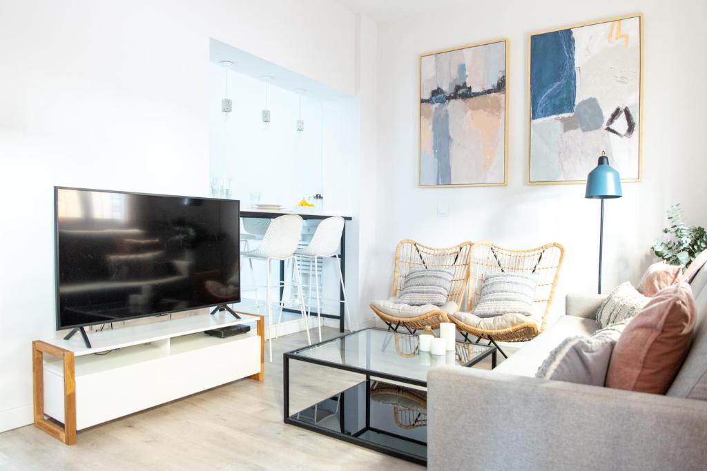 ein Wohnzimmer mit einem Sofa und einem TV in der Unterkunft Tinto Townhouse by Olala Homes in Sevilla