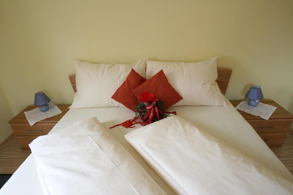 ザンクト・ファイト・アン・デア・グランにあるFerienwohnung Fischingerの白いシーツと赤い花が飾られたベッド