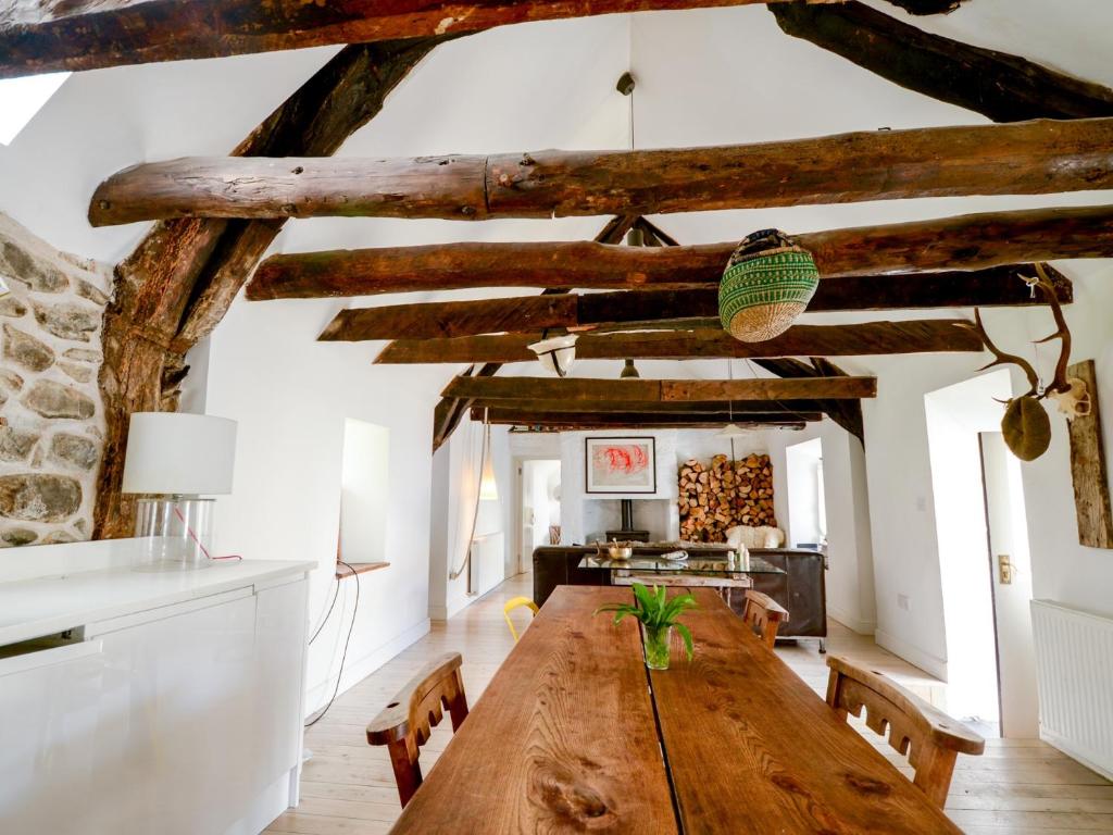 una gran mesa de madera en una sala de estar con vigas de madera. en The Croft where Architecture Meets Serenity, en Lochearnhead