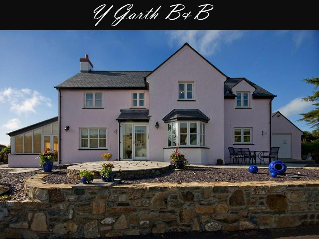 a large pink house with a stone wall at Y Garth Luxury Bed and Breakfast in Newport Pembrokeshire