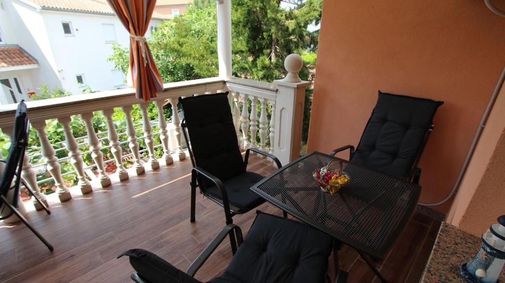 einen Balkon mit 2 Stühlen, einem Tisch und einem Fenster in der Unterkunft Apartment Kreslin in Vantačići