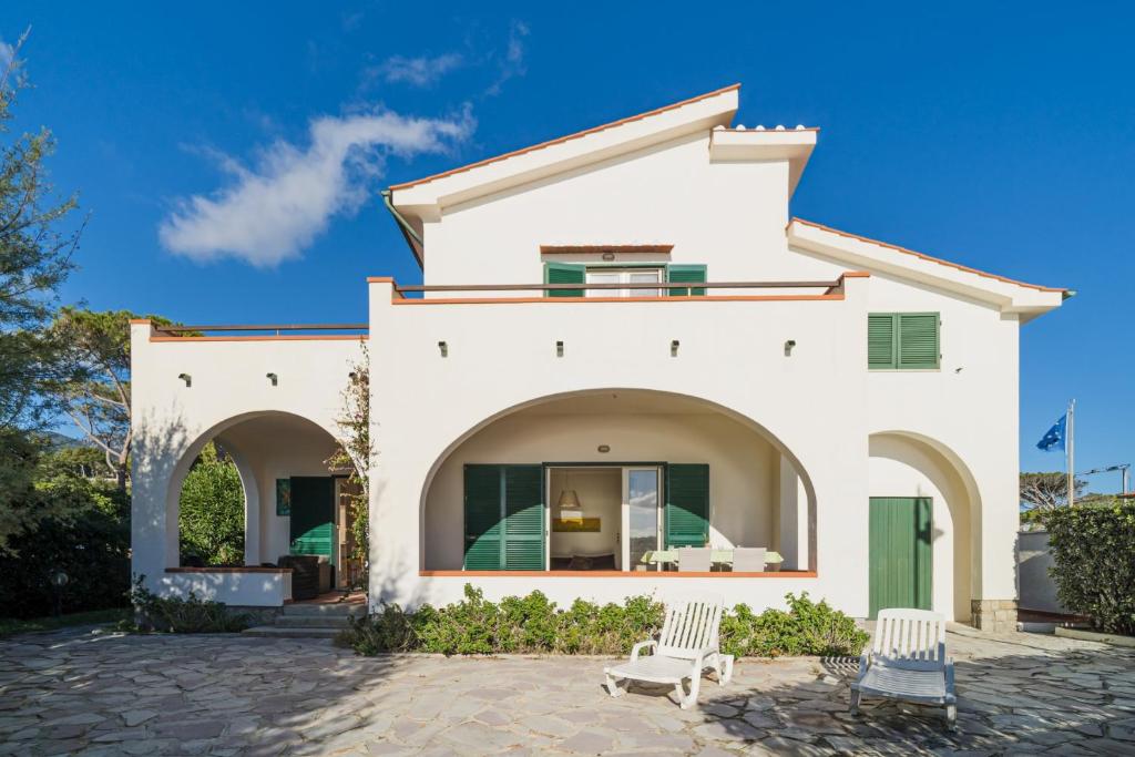 ein weißes Haus mit zwei Stühlen davor in der Unterkunft Villa Asteria - Goelba in Campo nell'Elba