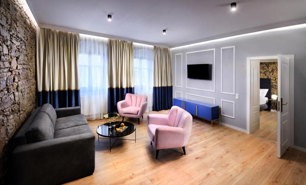 a living room with a couch and two pink chairs at Kalix Boutique Hotel in Poprad
