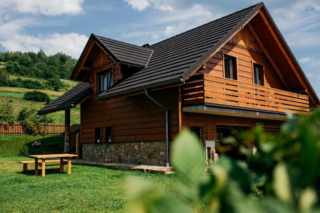 ein Holzhaus mit einer Bank davor in der Unterkunft Domek na Śmigowskim Piwniczna-Zdrój in Piwniczna-Zdrój