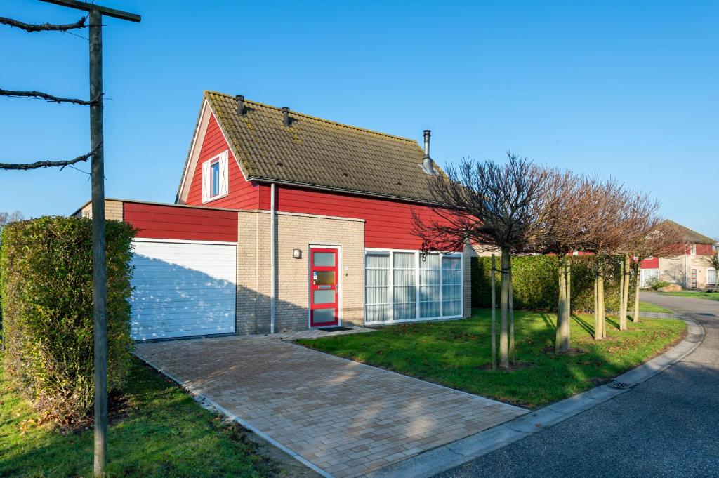 un granero rojo con una puerta roja en una calle en Antibes 280 - Kustpark Village Scaldia, en Hoofdplaat