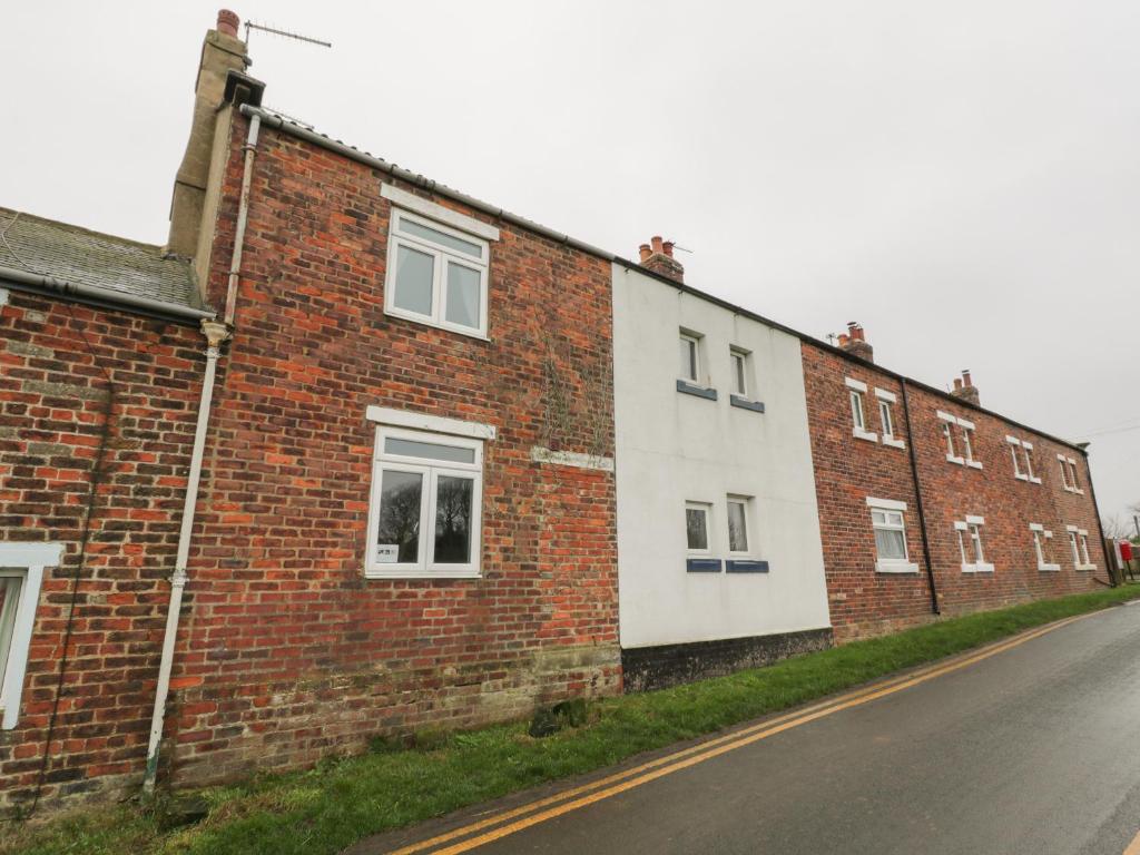 ein Backsteingebäude mit einer weißen Wand an einer Straße in der Unterkunft Mulgrave Cottage in Saltburn-by-the-Sea