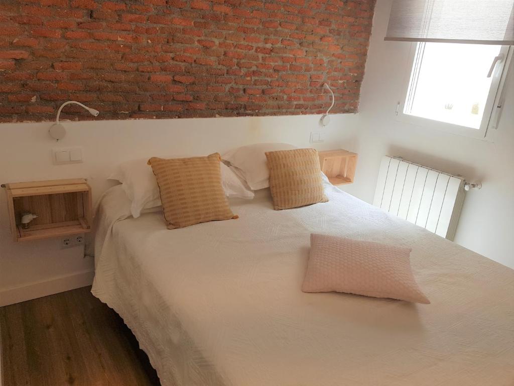 1 dormitorio con cama blanca y pared de ladrillo en Modern apartment, self check-in, Wi-Fi, Smart TV 55" 4K, en Madrid
