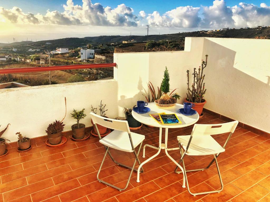 einen Tisch und Stühle auf einem Balkon mit Pflanzen in der Unterkunft CASA ABUELA MINA in Lomo de Arico