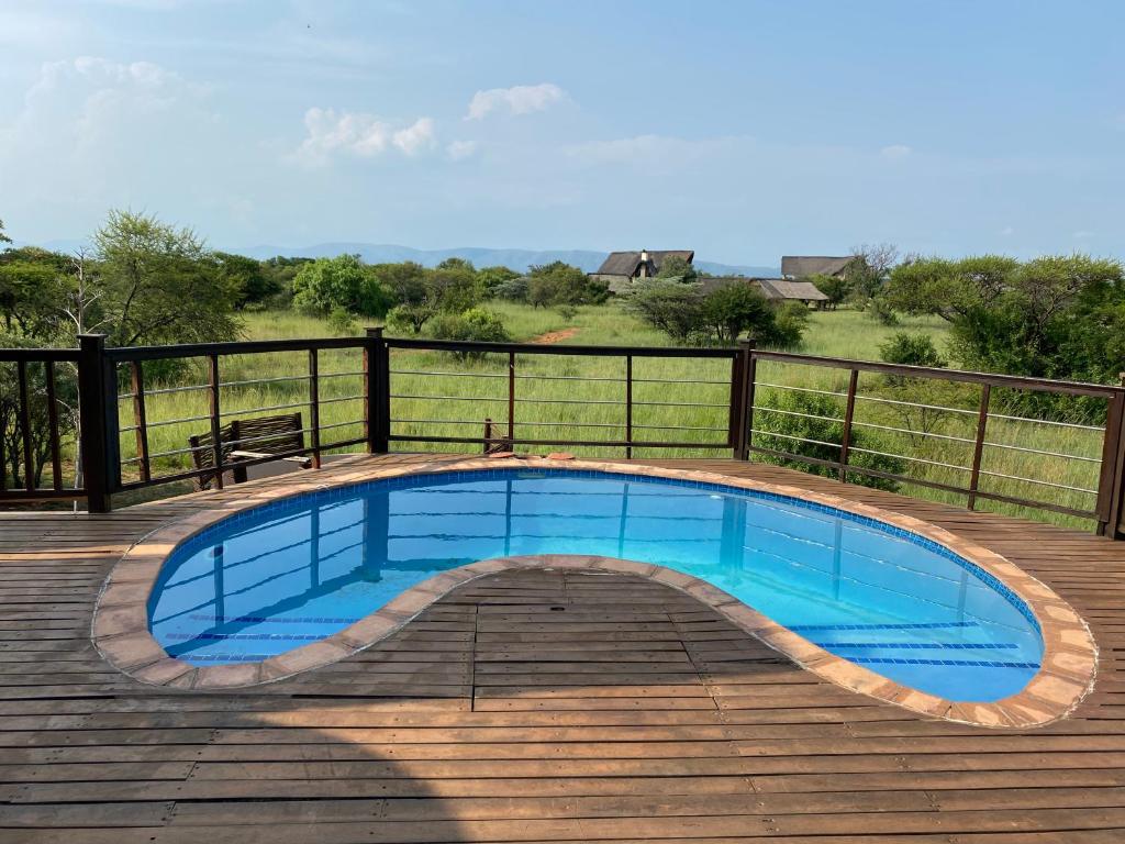 una piscina en una terraza de madera con un banco en Luna rossa 19 Zebula golf course and spa resort, en Mabula