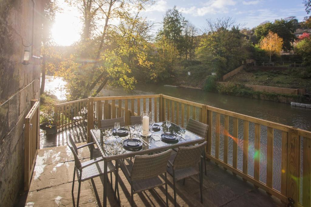 a table and chairs on a balcony with a river at The Bridge House in Bath