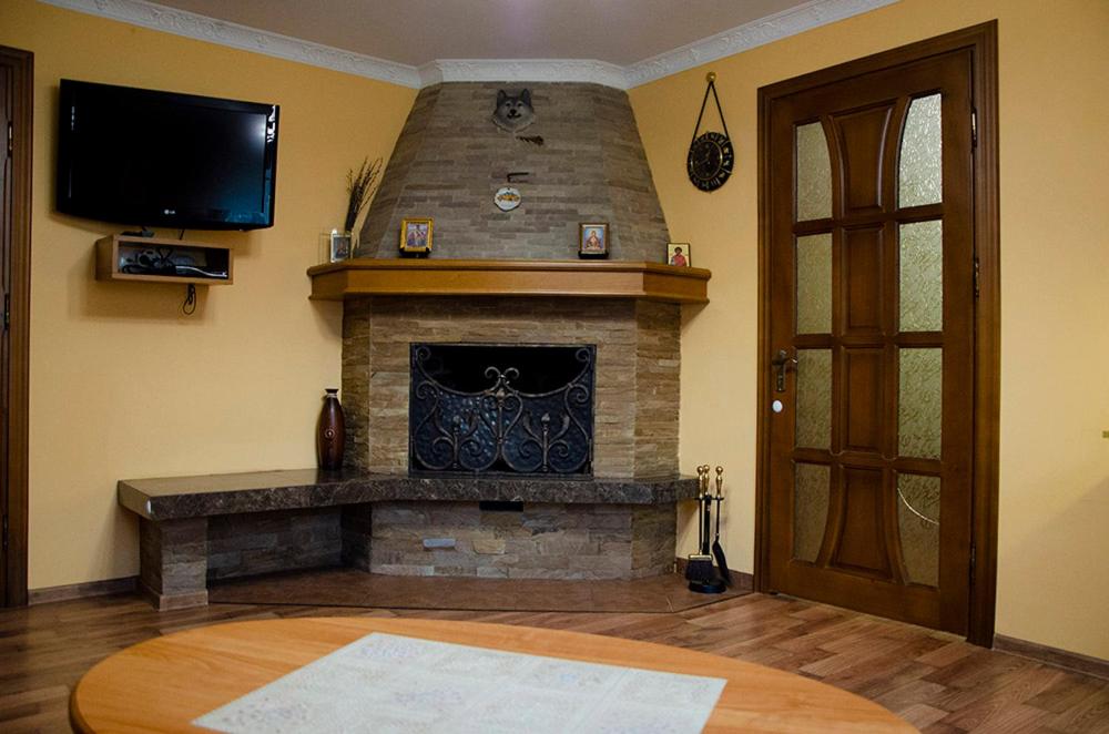 un salon avec une cheminée en pierre et une télévision dans l'établissement У Стрия, à Skhidnitsa