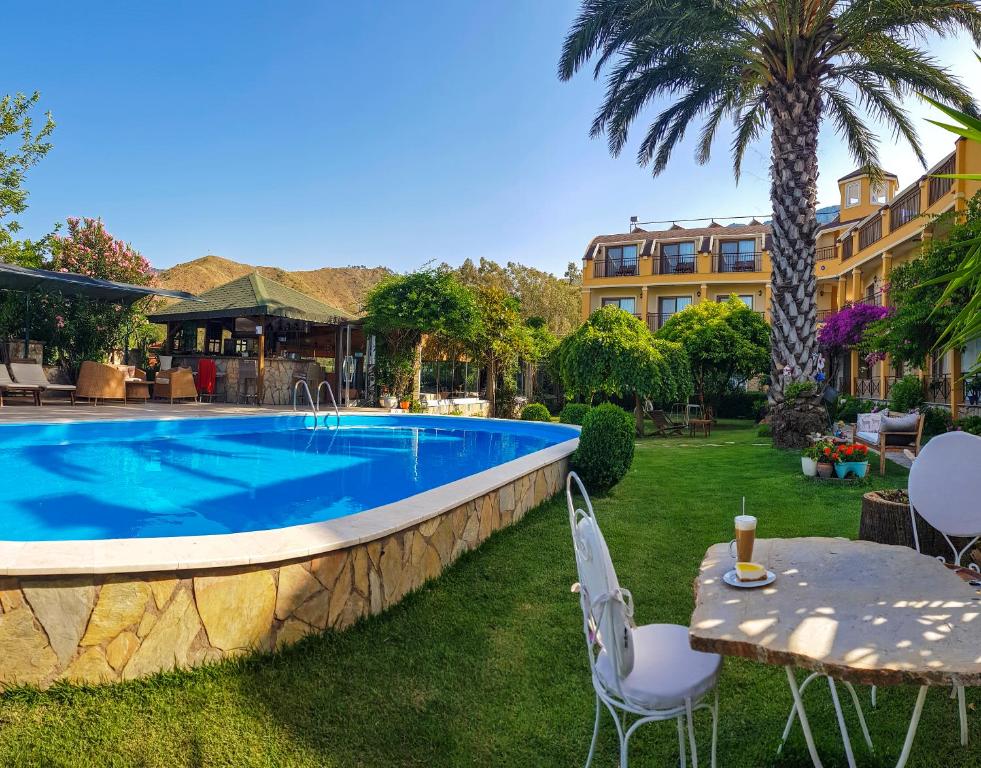 a swimming pool in a yard with a table and chairs at Papirus Hotel in Adrasan