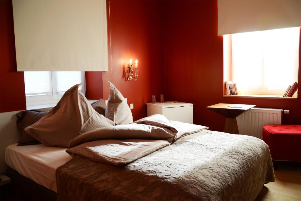 Schlafzimmer mit roten Wänden und einem Bett mit Kissen in der Unterkunft Le Presbytère in Differdingen