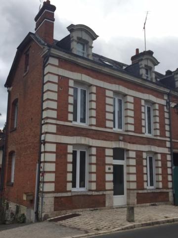 un bâtiment en briques avec deux cheminées au-dessus dans l'établissement Gîte Les Carelles, à Neung-sur-Beuvron