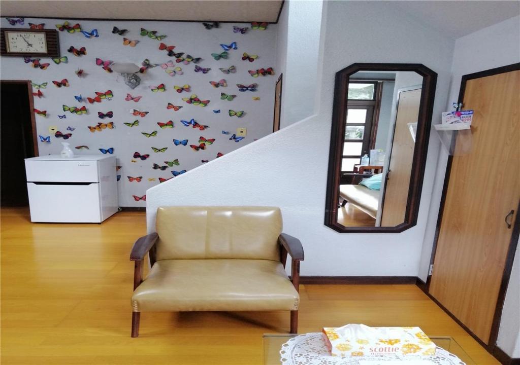 einen Stuhl in einem Zimmer mit Spiegel und Schmetterlingen an der Wand in der Unterkunft Guest house Hamayu - Vacation STAY 11558v in Katase