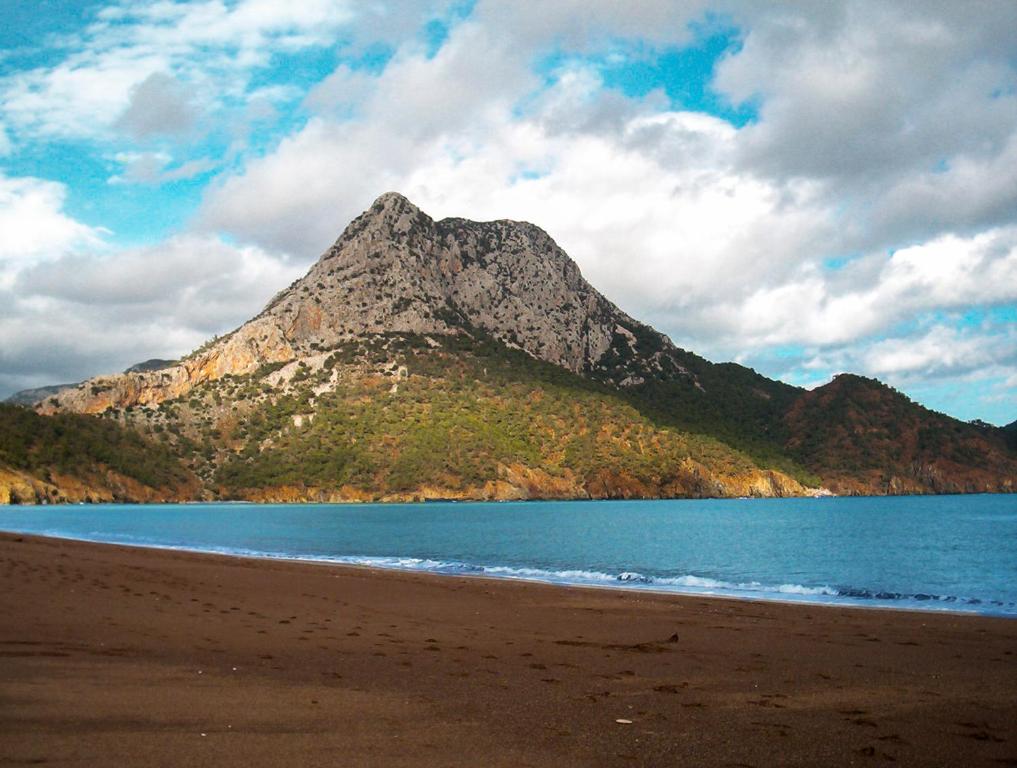 a mountain sitting on top of a beach next to the ocean at Papirus Hotel in Adrasan