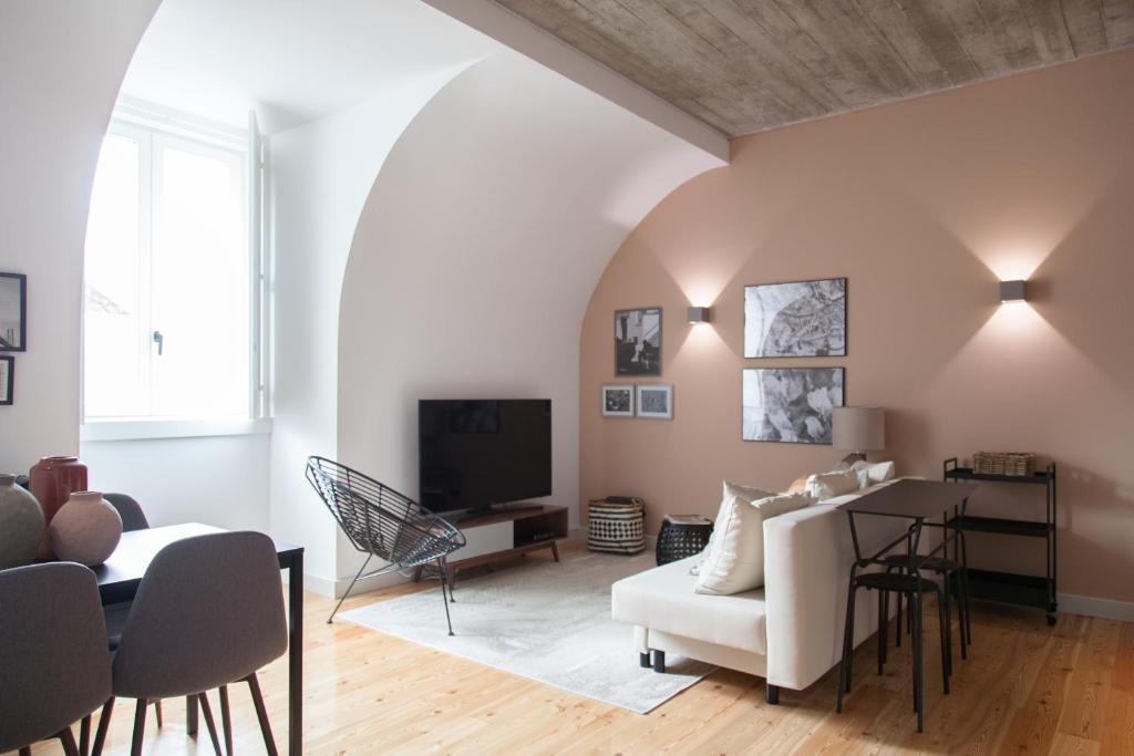 ein Wohnzimmer mit einem weißen Sofa und einem TV in der Unterkunft FLH Intendente Charming Flat in Lissabon